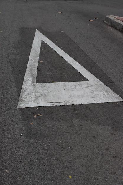 What does a white triangle painted on the road mean? 